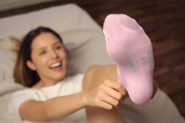 Frau zieht lachend rosa Socken an